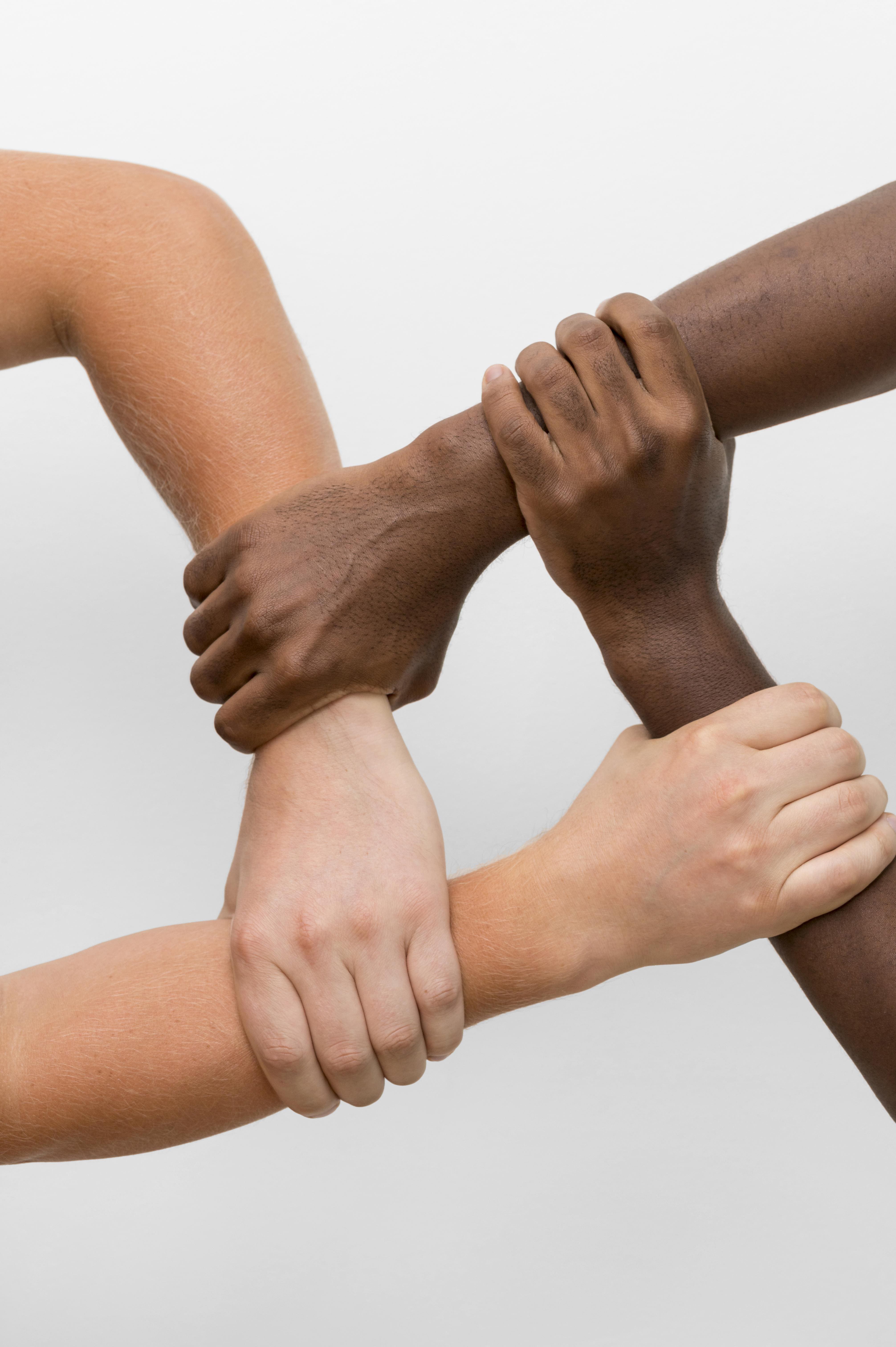 Depicts four arms of different skin tones, interlocked in a show of unity